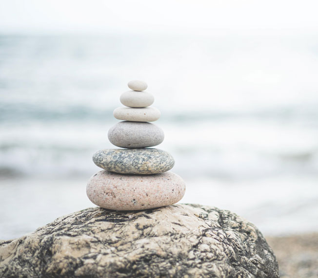 Stacked balancing stones on a rock beside calm water